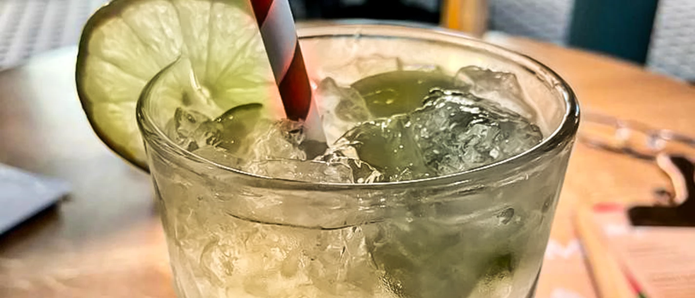 Limonade_CCBYSA_Teutoburger Wald_Stadt Schloss Holte-Stukenbrock-16.jpg Erfrischende limonadengrüne Getränkeglas mit Eiswürfeln, Limettenscheibe und gestreiftem Strohhalm.