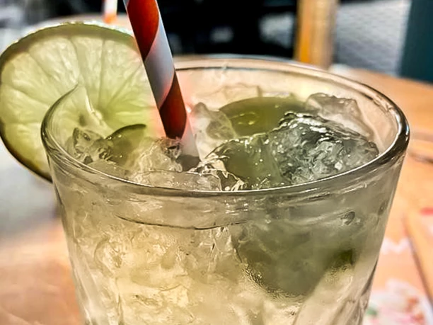 Limonade_CCBYSA_Teutoburger Wald_Stadt Schloss Holte-Stukenbrock-16.jpg Erfrischende limonadengrüne Getränkeglas mit Eiswürfeln, Limettenscheibe und gestreiftem Strohhalm.