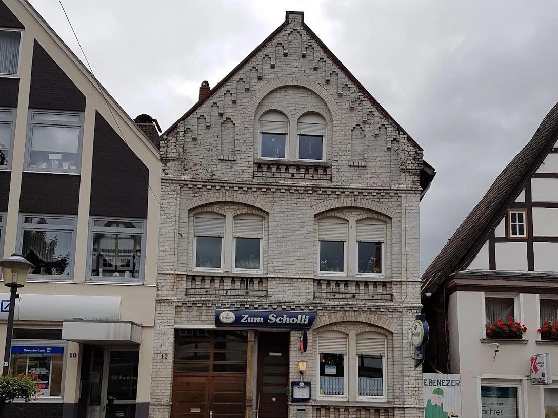 Zum Scholli.jpg Restaurant Zum Scholli in historischem Gebäude mit verzierter Fassade und traditionellen Fenstern.