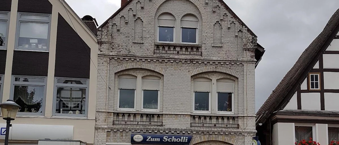 Zum Scholli.jpg Restaurant Zum Scholli in historischem Gebäude mit verzierter Fassade und traditionellen Fenstern.