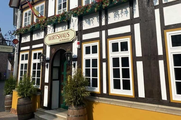 Wirtshaus Blomberg.jpg Historisches Fachwerkhaus mit Schild "Wirtshaus", Blumendekoration und hölzernem Eingangsbogen.