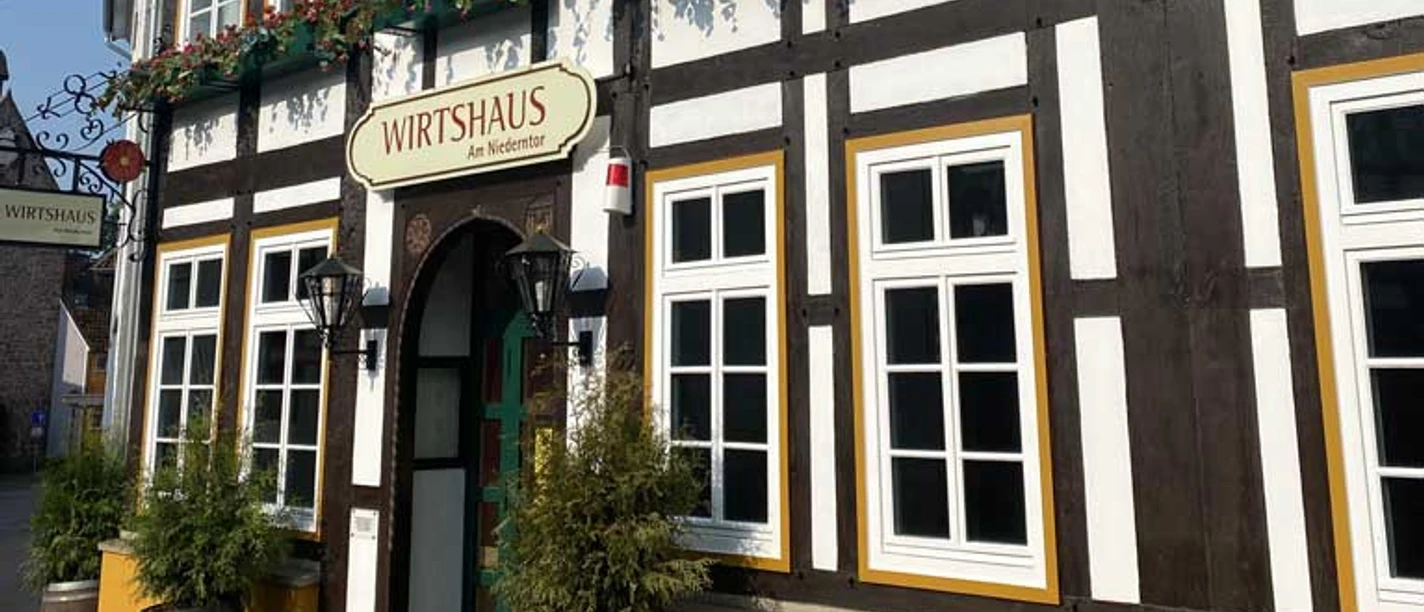 Wirtshaus Blomberg.jpg Historisches Fachwerkhaus mit Schild "Wirtshaus", Blumendekoration und hölzernem Eingangsbogen.