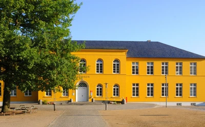 Rathaus Ratzeburg mit Tourist-Information und Standesamt.jpg Vor dem Rathaus gibt es einen Platz mit einem Baum. Unter dem Baum stehen Sitzbänke
