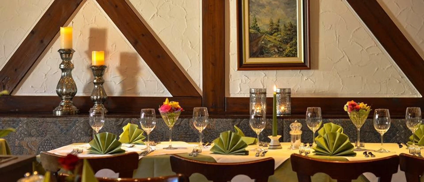 Einladendes Restaurant mit elegant gedeckten Tischen, Holzdetails und dezenter Beleuchtung.