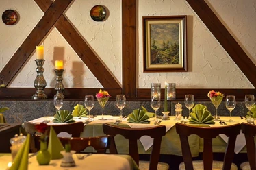 Adria Restaurant Innen.jpg Einladendes Restaurant mit elegant gedeckten Tischen, Holzdetails und dezenter Beleuchtung.