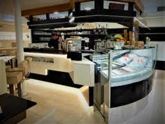Eiscafe italia uno due.jpg Innenansicht eines modernen Eiscafés mit beleuchtetem Tresen, Glastheke und verschiedenen Eiscremesorten.