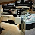 Eiscafe italia uno due.jpg Innenansicht eines modernen Eiscafés mit beleuchtetem Tresen, Glastheke und verschiedenen Eiscremesorten.