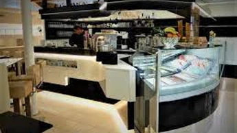 Eiscafe italia uno due.jpg Innenansicht eines modernen Eiscafés mit beleuchtetem Tresen, Glastheke und verschiedenen Eiscremesorten.