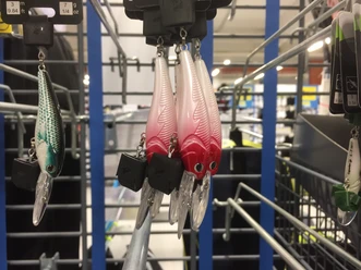 Verschiedenfarbige Angelköder in einem Geschäft, organisiert an einem Metallständer mit Details sichtbar.