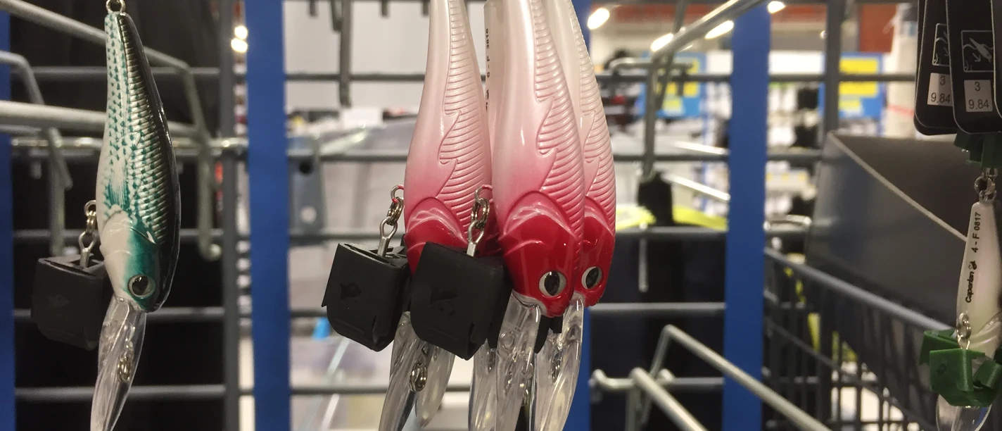 Verschiedenfarbige Angelköder in einem Geschäft, organisiert an einem Metallständer mit Details sichtbar.