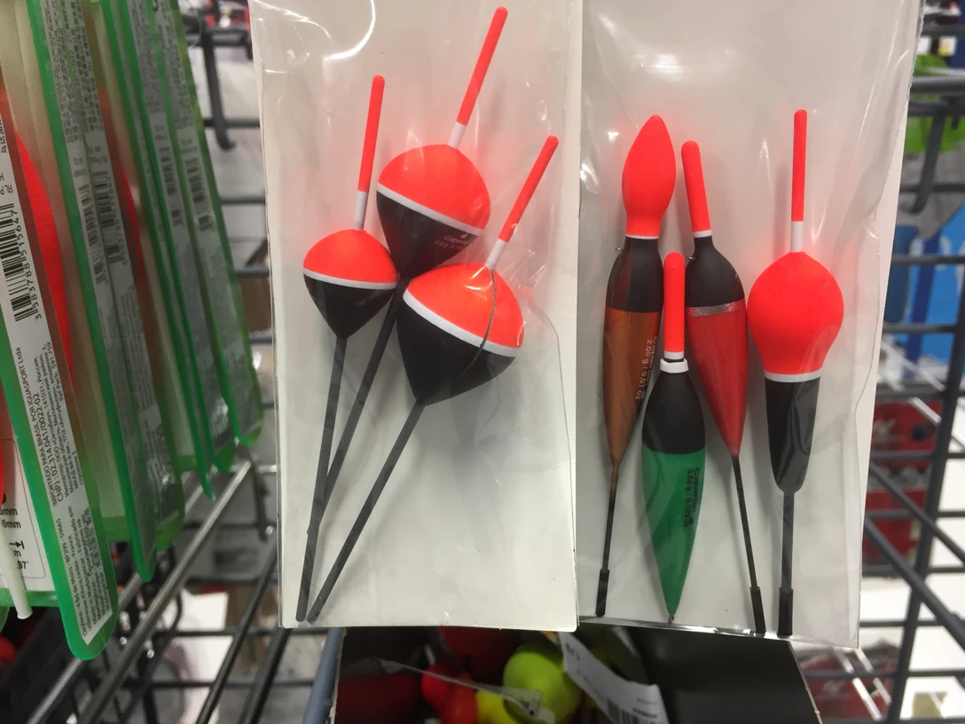 In einem Anglergeschäft hängen in Folien verpackte bunte Schwimmer verschiedener Formen und Größen.
