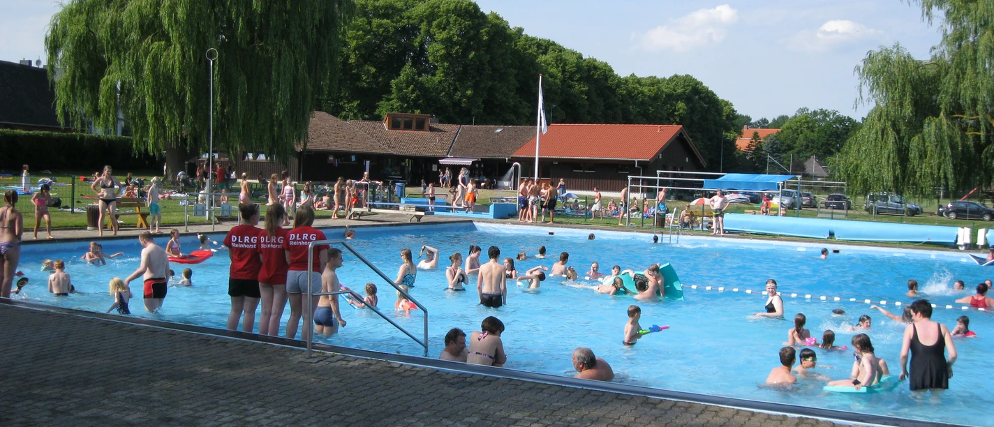 Freibad Steinhorst Outdoor pool with many people swimming and relaxing on a sunny day in a green park setting