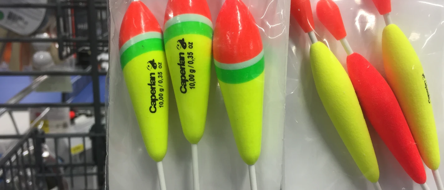 Verschiedene leuchtend bunte Angelschwimmer, in Regalen aufgehängt, perfektes Zubehör für Angler.