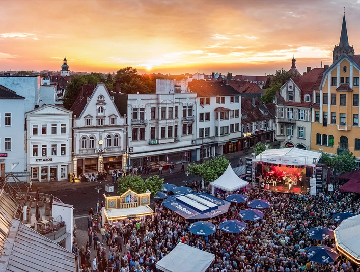 Menschengedrängte Festveranstaltung in Herford mit Bühnen und Ständen vor historischer Architektur.