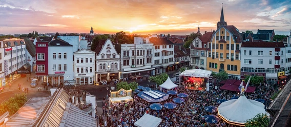 Teutoburger Wald Tourismus_Herford_Hoeker-Fest Menschengedrängte Festveranstaltung in Herford mit Bühnen und Ständen vor historischer Architektur.