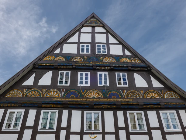 Werner Wilmes-AltHorn-Nordstrasse.jpg Fachwerkhaus mit verziertem Giebel und weißen Fenstern, eingerahmt von einem blauen Himmel.