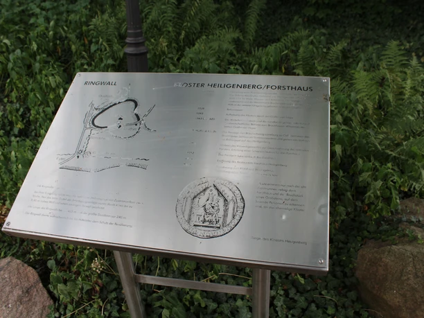 Information sign at the site of the Heiligenberg ring wall, surrounded by green spaces and stones.