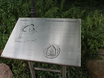 Ringwall Heiligenberg Infotafel am Standort des Ringwalls Heiligenberg, umgeben von Grünflächen und Steinen.