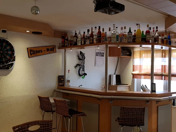 Aufenthaltsraum Ein lebendiger Aufenthaltsraum mit gut bestückter Bar, Dartscheibe und gemütlichen Sitzgelegenheiten.