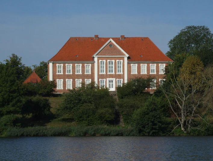Kreismuseum Herzogtum Lauenburg.JPG Blick vom Ufer auf das Kreismuseum: rotes Gebäude mit weißen Fenstern, davor Wasser und Uferbereich mit Grün