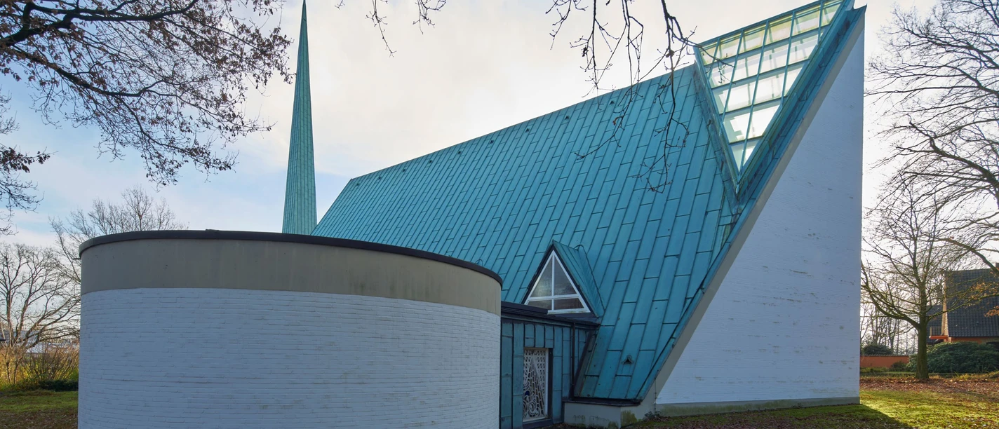Bonnuskirche in Osnabrück Eine moderne Kirche mit blauer Dachkonstruktion und rundem Anbau in einer grünen Umgebung.