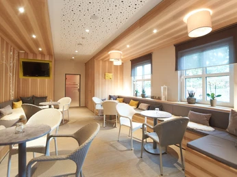 Aqualip Saunalounge Moderne Lounge mit Holzwänden, gemütlichen Sitzgelegenheiten, großen Fenstern und entspannter Beleuchtung.