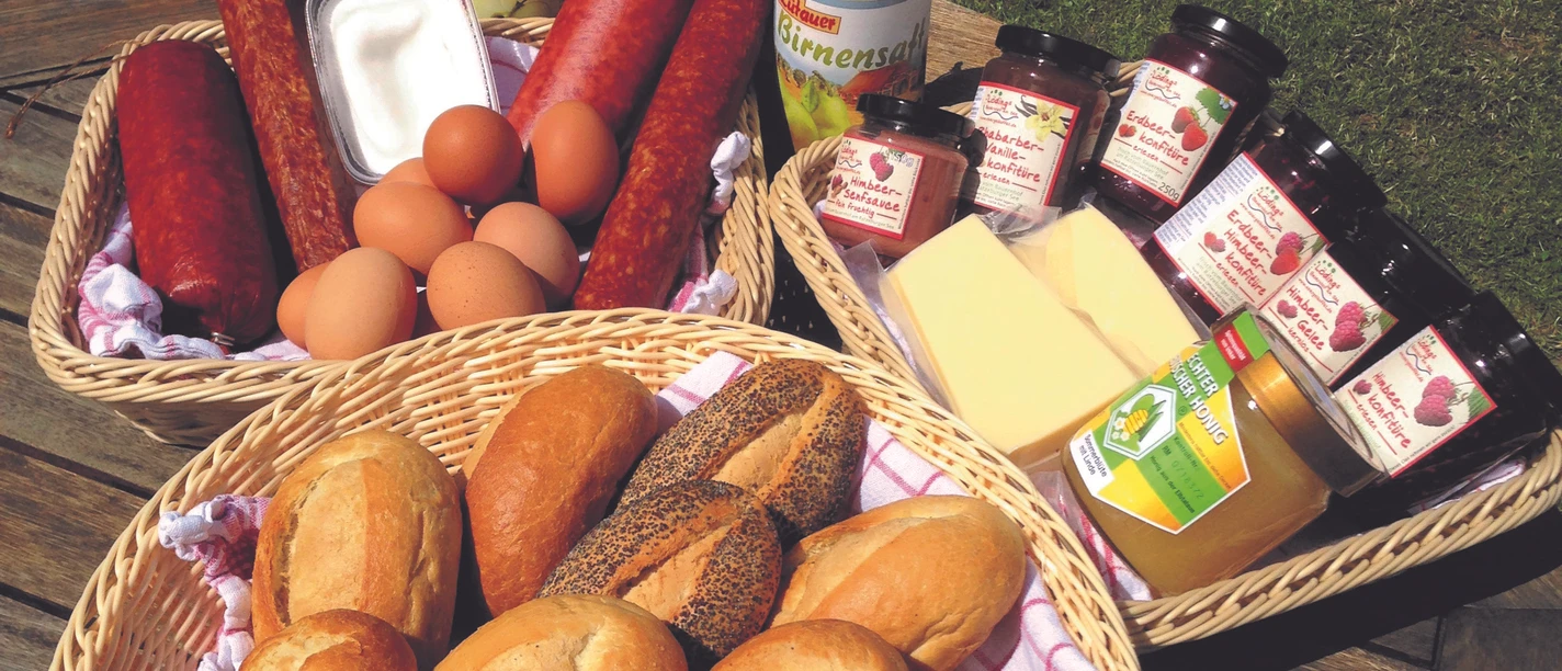 Lödings Bauernhof am See_Frühstück.jpg Blick auf verschiedene Waren wie Käse, Wurst, Eier und andere Lebensmittel