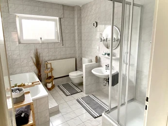 IMG-20220930-WA0022.jpg Modernes, helles Badezimmer mit Dusche, Badewanne, Waschbecken und WC. Zwei graue Badvorleger.