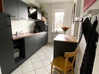 IMG-20220930-WA0023.jpg Moderne Einbauküche in dunklem Grau, mit Holzarbeitsfläche, Licht flutet durch das Fenster ein.