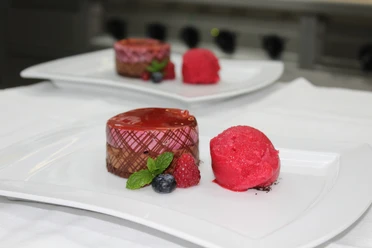 Bergische Genusstage Zwei Teller mit Dessert: Schokoladenmousse-Törtchen und Sorbet, garniert mit frischen Beeren und Minze.