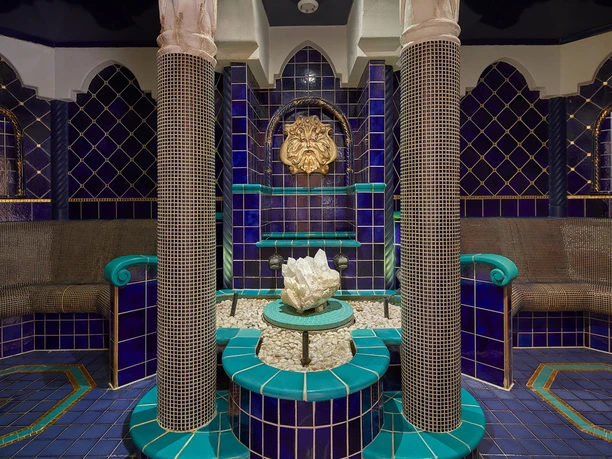 Toskana Therme Bad Schandau: Ein luxuriöser Spa-Raum mit blauen und türkisfarbenen Fliesen, einer zentralen Kristallskulptur und dekorativen Säulen in entspannter Atmosphäre.