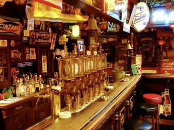 brösel.jpg Traditionelle Kneipe mit historischen Schildern, langer Holztheke und Zapfanlage, umgeben von Barhockern.