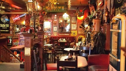 Brösel 2.jpg Ein gemütliches, rustikales Pub mit Holztischen und Wänden voller vielfältiger Dekorationen.