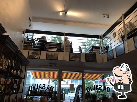 Da-Salvo-design.jpg Restaurant mit Galerie, zeigt Gäste beim Essen auf einer erhöhten Plattform, umgeben von Regalen.