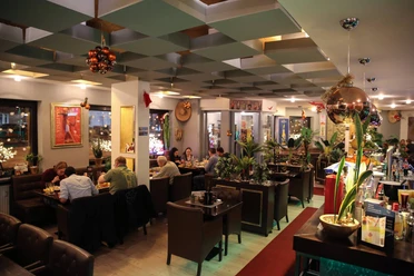 15874658_598438367015844_7804153406967349204_o.jpg Das Bild zeigt die Innenansicht des Restaurants an einem lebendigen und gut besuchten Nachmittag. Die Einrichtung ist klassisch und erzeugt ein familiäres Ambiente.