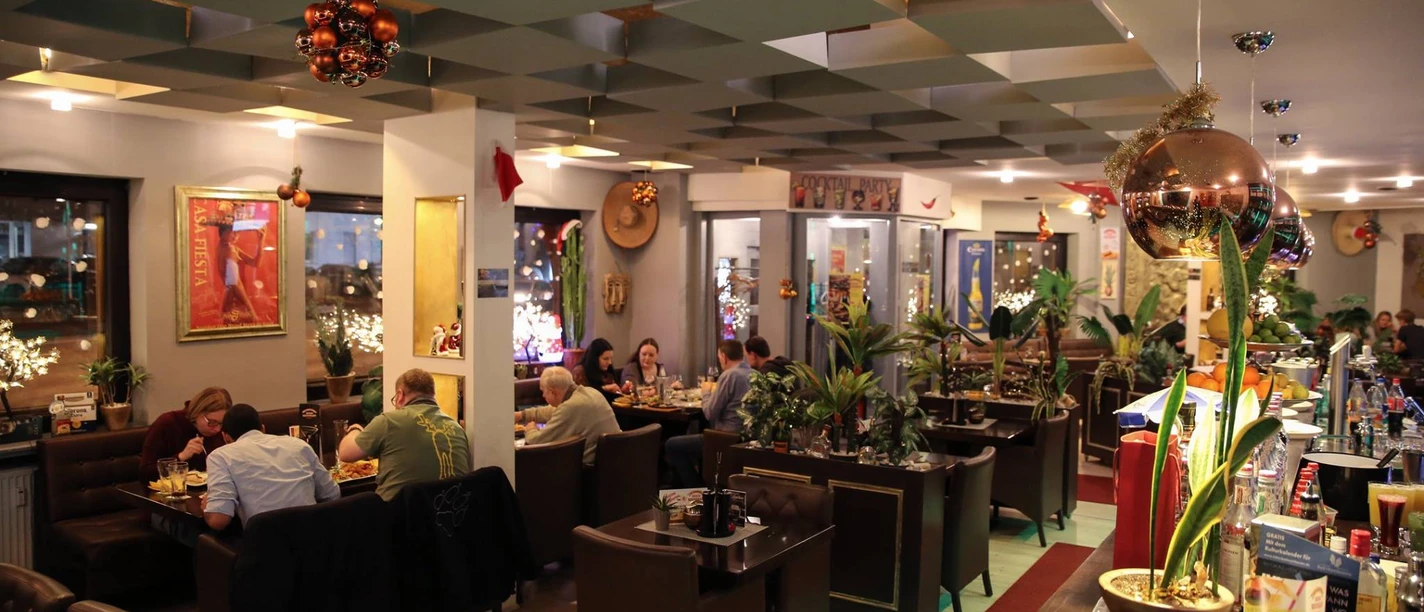 El Sombrero Innenraum.jpg Das Bild zeigt die Innenansicht des Restaurants an einem lebendigen und gut besuchten Nachmittag. Die Einrichtung ist klassisch und erzeugt ein familiäres Ambiente.