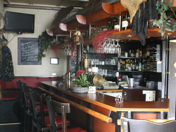 198316_579077618819432_1908490432_n.jpg Zu sehen ist die braune Theke des Hexenhäuschens. Vor der Theke stehen Barhocker. Zudem ist die Dekoration in Braun, Rot und Schwarz.