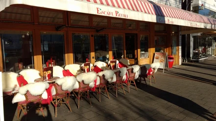 28616543_1876379535705811_6119886081932960166_o.jpg Das Bild zeigt den Außenbereich des Eiscafes PiccolIis. Man erkennt viele gemütliche Sitzgelegenheiten.