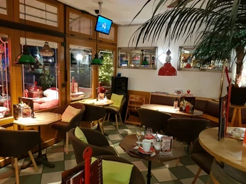 28827486_1876380122372419_3636265100731590552_o.jpg Das Bild zeigt die Innenansicht des Eiscafes. Die Einrichtung ist in braunen und warmen Tönen gehalten.