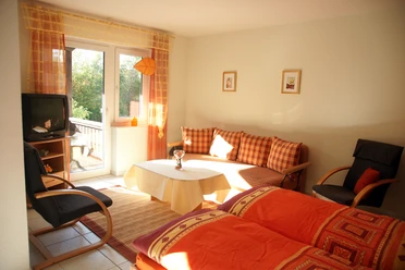 20.jpg Helles Wohnzimmer mit Sofa, Sessel und Tisch, durch Fensterblick auf grüne Natur in Preußisch Oldendorf.