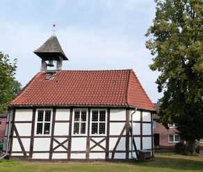 mardorf-kirche.JPG Historische Fachwerkkirche mit Glockenturm und rotem Ziegeldach, umgeben von grünem Rasen und Bäumen.