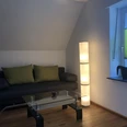 Wohnzimmer Ein modernes Wohnzimmer mit einem grauen Sofa, einem glastisch und einer hohen, leuchtenden Stehlampe.