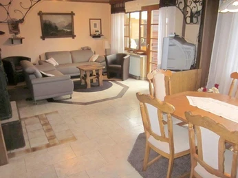 Wohnzimmer Ein Wohnzimmer mit Ledersofas, einem Holztischset und einem Röhrenfernseher auf einem Sideboard.