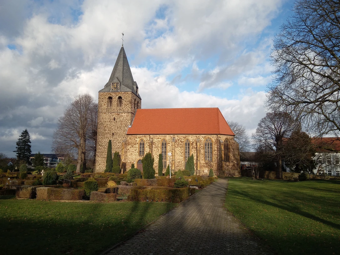 Historische Kirche St. Nikolaus, Backsteingotik mit markantem Turm, umgeben von grün gepflegter Anlage.