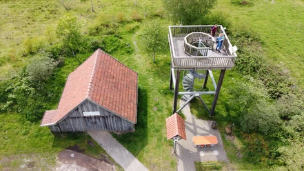 Kapellenmoorgraben_Niederlangen_ Aussichtsturm Informationshütte ©Naturpark Hümmling e. V. (8).jpg Holzturm mit Aussichtsplattform neben einer kleinen Informationshütte in grüner Moorlandschaft