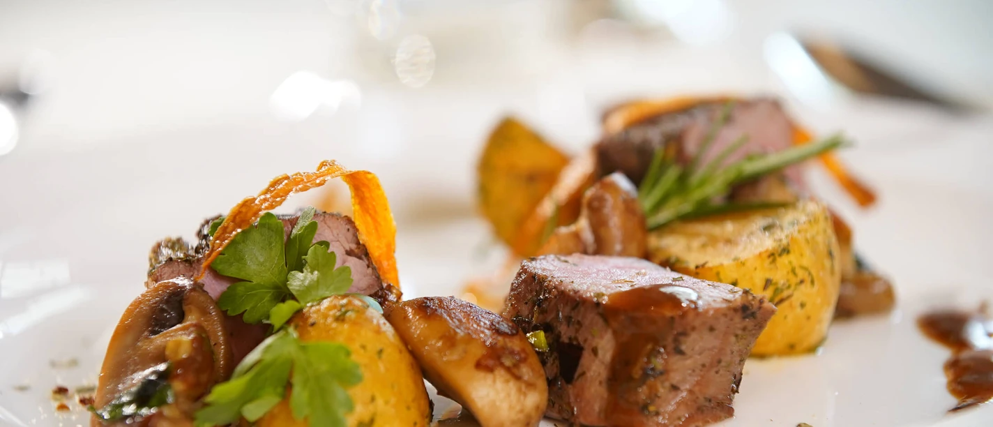 Finely prepared dishes with potatoes, succulent meat and herbs on a white plate.