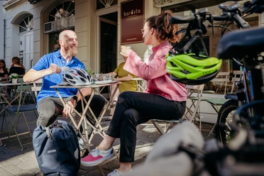 Two people enjoy drinks in the sunshine at an outdoor table at Café Barösta in Osnabrück.