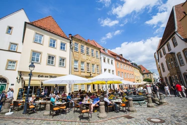 Café am Markt Menschen genießen sonnige Stunden vor einem historischen Café in einer belebten Altstadtkulisse.