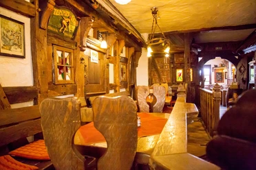 Rustiek, traditioneel restaurant met houten meubels en warme verlichting in een historische omgeving.