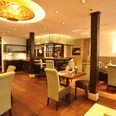 Elegant restaurantinterieur met houten tafels, gestoffeerde stoelen en moderne verlichting.